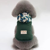 Cute dog wearing a stylish green coat with a camouflage hood from TAILTRAIL for winter warmth.