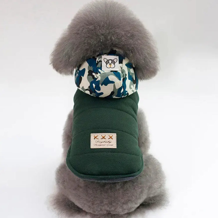 Cute dog wearing a stylish green coat with a camouflage hood from TAILTRAIL for winter warmth.